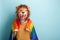 Young woman in lion mask hold rainbow lgbt pride flag wrapped around the shoulders, isolated on blue