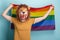 Young woman in lion mask hold and wave pride rainbow lgbt flag in her hands behind head