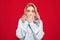 Young woman listen bad news. Shocked girl covering mouth with hands for mistake, isolated on red background. Scared female