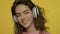 Young woman listen music in headphones. Happy girl in headphone on yellow