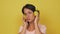 Young woman listens to music in large headphones on a yellow background. Woman dances in headphones in the studio. High