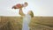 Young woman with little baby playing fun in the field with bales summer evening at sunset. Cute mother in dress and her