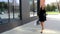 Young woman in little black dress spins around on the street. Beautiful fair-skinned young lady in black dress moves