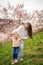 Young woman with little daughter in a blooming pink and white garden Petrin in Prague, spring time in Europe