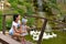 A young woman with a little daughter on the bridge in the Park watching the swans floating