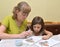 The young woman with the little daughter paint with paints a birds feeder