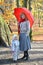 The young woman with the little daughter stand under a red umbrella in the autumn park