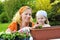 Young woman and little girl gardening in spring, planting flower seedlings, smiling mother and her happy child working in garden