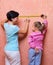 Young woman and little girl with measuring tape