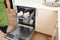 Young woman loading dishwasher in kitchen