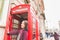 Young woman in London in front of a typical red phone booth