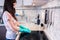 Young woman with long dark hair cleans a black cooker panel