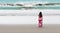 Young woman in long dress walks towards the ocean