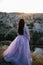 Young woman with long, flowing dress on a hilltop, admiring the majestic mountain range