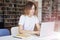 Young woman long hair analyst working at co-working office on laptop, bookshelf behind. Businesswoman learning alone in library