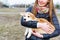 Young woman with long hair holding small corgi dog outdoors