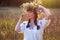 A young woman in a long white embroidered shirt puts a wreath on