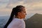 Young woman looking at amazing sunset in mountains. Cornrows hairstyle