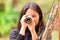 Young woman looking through black monocular in the forest in a blurred background