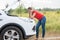 Young woman looking at broken car and waiting for help n the rural road