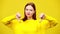 Young woman looking at camera showing thumbs down in slowmo at yellow background. Portrait of Caucasian lady