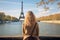 Young woman looking at Eiffel Tower in Paris, France, Young traveler woman rear view sitting on the quay of Seine River looking at