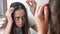 Young woman is looking at her hairs in front of the mirror in bathroom.