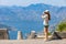 Young woman looking at Kotor bay in Montenegro through binoculars at view spot on serpantine road