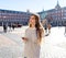 Young woman looking at smart mobile phone in Plaza Mayor Madrid feeling lost looking for directions