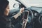 Young woman looking to her smartphone while driving car at front window background. Distracted female driver. Concept of