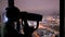 Young woman looking through tourist telescope and exploring night cityscape