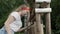 Young woman looking in wooden bucket on water well in summer countryside. Rustic young woman checking water in bucket on