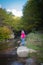 A young woman looks and admires the beautiful waterfall in autumns,