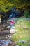 A young woman looks and admires the beautiful waterfall in autumns,