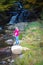 A young woman looks and admires the beautiful waterfall in autumns,