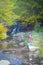 A young woman looks and admires the beautiful waterfall in autumns,