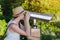 Young woman looks through binoculars for tourists at viewpoint on Park background