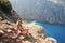 Young woman looks at Butterfly Valley from above, sitting on the rocks. Landscape Oludeniz, Turkey