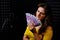 A young woman looks at the money in the recording studio standing at the microphone. Singer with a pack of euros in cash.