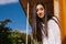 A young woman looks out from the balcony.The bright sun shines on the girl. Beautiful brunette girl enjoys the sun