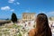 Young woman looks at Parthenon on the Acropolis of Athens, Greece. The famous ancient Greek Parthenon is the main tourist attract