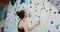 A young woman lowers a safety rope after her own descent from a climbing wall