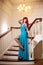 Young woman with luxurious long beautiful red hair in a blue fashionable evening dress in the rich interior.