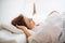 A young woman lying in bed indoors in the morning in a bedroom, sleeping.