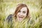 Young woman makes crazy face in wheat field by sunset