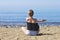 Young woman makes meditation in lotus pose on sea / ocean beach, harmony and contemplation. Beautiful girl practicing yoga at sea