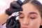 Young woman making eyebrow cosmetic procedure. Eyebrow shaping master service her client female