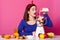 Young woman making healthy smoothie. Slender female with opened mouth adds milk to blender. Suprised girl dresses shirt and red