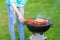 Young woman is making meat barbecue in the garden on the green grass