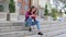 Young woman making mobile photo on the street sitting on the steps